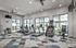Modern fitness center boasting state-of-the-art treadmills, elliptical machines, and vibrant patterned flooring, complemented by large windows for natural light.