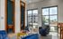 Bright and modern apartment lounge with plush blue chairs, vibrant cushions, and large windows offering abundant natural light and scenic views.