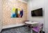 Cozy modern meeting room with vibrant abstract wall art, stylish purple chairs, and a mounted flat screen TV.