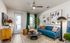 Chic living room with a vibrant blue sofa, modern art, and elegant decor in a bright, airy space.