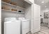Modern laundry room with sleek washer and dryer, ample storage on open shelving, and elegant flooring.