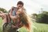 Joyful couple embracing in a sunlit field, capturing a moment of carefree happiness and love amidst the lush greenery.