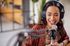 Enthusiastic woman with headphones smiling while recording in a modern studio setting.