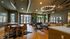 Elegant apartment lounge featuring modern decor, a cozy seating area with stylish chairs, large windows with natural light, and contemporary lighting fixtures.