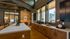 Inviting kitchen space with large windows, warm wood cabinetry, and a sleek countertop, enhanced by stylish modern decor.