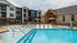 Luxurious apartment complex featuring a sparkling outdoor pool with modern sun loungers, surrounded by elegant buildings and a stylish communal area.