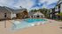 Inviting outdoor apartment pool area with modern loungers, surrounded by lush greenery and contemporary architecture.