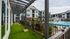 Modern apartment complex exterior featuring lush green lawns, stylish pergola, and inviting pool area with sun loungers.