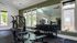 Modern fitness center with large mirrors, a variety of exercise machines, and natural light streaming through expansive windows.