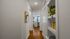 Inviting hallway with elegant wooden floors, leading to a well-lit kitchen and living area, accented by modern decor and vibrant greenery.