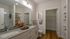 Elegant bathroom featuring a granite countertop, double sinks, modern shower, and spacious walk-in closet.