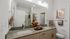 Modern bathroom with twin granite vanities, sleek cabinetry, and stylish decor, featuring ambient lighting and tasteful artwork.