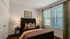 Inviting bedroom with modern decor featuring a cozy bed, elegant nightstands, and large windows with lush curtains for natural light.
