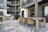Modern upscale patio with wicker chairs and stone tiles, offering a perfect blend of luxury and comfort for outdoor dining.