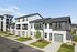 Modern apartment complex showcasing stylish architecture with balconies and spacious garages, surrounded by lush greenery and well-maintained pathways.