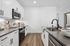 Contemporary kitchen with sleek white cabinetry, stainless steel appliances, and elegant dark countertops.