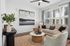 Bright and modern living room with elegant d&eacute;cor, featuring a cozy beige sofa, stylish artwork, and large windows letting in natural light.