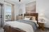 Bright and inviting bedroom with stylish decor, featuring a cozy bed, large window with views, and elegant bedside lighting.
