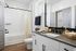 Bright contemporary bathroom featuring elegant black fixtures, a sleek countertop, and a bathtub with modern finishes.