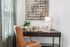 Chic home office with a modern desk, stylish artwork, and a cozy leather chair, bathed in natural light.