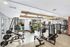 Modern apartment gym with state-of-the-art equipment, sleek design, and large windows offering natural light.