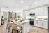 Modern kitchen with sleek white cabinetry, a spacious island with chic bar stools, and elegant decor, offering a welcoming and airy atmosphere.