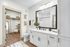 Elegant bathroom with modern fixtures, featuring a dual-sink vanity, large framed mirror, and walk-in closet with ample storage.