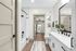 Elegant bathroom with modern fixtures, showcasing a sleek vanity, a spacious mirror, and a stylish shower area with tasteful decor.