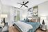 Inviting bedroom with plush bedding, stylish artwork, and natural light through large windows.