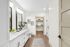 Luxurious and modern bathroom with elegant double vanity, sleek mirrors, and walk-in closet, offering a serene blend of style and functionality.