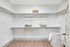Spacious, modern walk-in closet featuring elegant wooden hangers and stylish storage baskets on sleek white shelving.