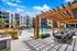 Luxurious apartment community showcasing a stylish outdoor pool area with modern lounge chairs, shaded seating under a pergola, and pristine landscaping.