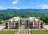 Modern apartment complex nestled in lush, scenic landscape with large, inviting building facade and ample parking.