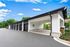 Chic modern covered parking area with sleek black doors and surrounding lush greenery, set under a flawless blue sky.