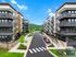 Modern apartment complex with stylish balconies, lush landscaping, and a scenic mountain backdrop.