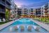 Elegant apartment complex featuring a luxurious swimming pool surrounded by stylish lounge chairs and modern architecture, perfect for relaxation and leisure.