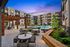 Chic contemporary apartment courtyard featuring a sparkling pool, stylish seating areas, and lush greenery under a beautiful twilight sky.