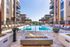 Luxurious apartment complex showcasing a stunning outdoor pool area with sun loungers, a cozy fire pit, and modern architecture.