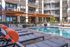 Luxurious apartment complex featuring a pristine swimming pool surrounded by stylish lounge chairs and modern architecture.