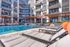 Modern apartment complex with a luxurious outdoor pool area, surrounded by stylish lounge chairs and elegant architecture.