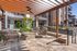 Inviting outdoor lounge area with comfortable seating under a stylish pergola, surrounded by lush greenery, perfect for relaxation and social gatherings.