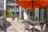 Luxurious outdoor terrace featuring stylish seating, vibrant orange umbrella, and modern BBQ grill set amidst a chic apartment complex.