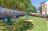Beautiful pet-friendly play area with agility equipment, lush green grass, and a modern apartment backdrop.