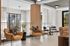 Modern apartment lounge featuring chic leather armchairs with patterned pillows, a cozy dining area, and floor-to-ceiling windows for abundant natural light.