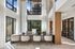 Elegant modern office space with floor-to-ceiling windows offering abundant natural light, featuring a sleek design with comfortable seating and a large communal desk.