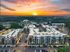 Breathtaking aerial view of modern apartment complex against a stunning sunrise backdrop, combining urban living with serene natural surroundings.