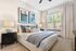 Elegant bedroom featuring a cozy bed with plush pillows, modern decor, and abundant natural light from large windows with stylish curtains.