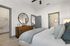 Chic bedroom with elegant decor, featuring a cozy bed, wooden dresser with a round mirror, and a spacious walk-in closet.