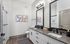 Luxurious bathroom featuring a sleek double sink vanity, elegant frameless shower, and modern decor with stylish artwork.