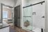 Modern bathroom with glass shower enclosure and contemporary finishes adjacent to a cozy, well-lit bedroom.